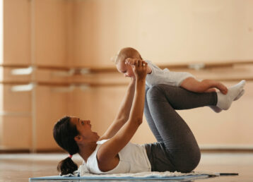 Cheerful mother having fun with her baby while working out in health club.